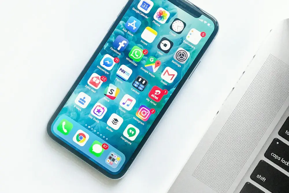 Sosyal medya uygulamalarının göründüğü akıllı telefon, yanında dizüstü bilgisayar